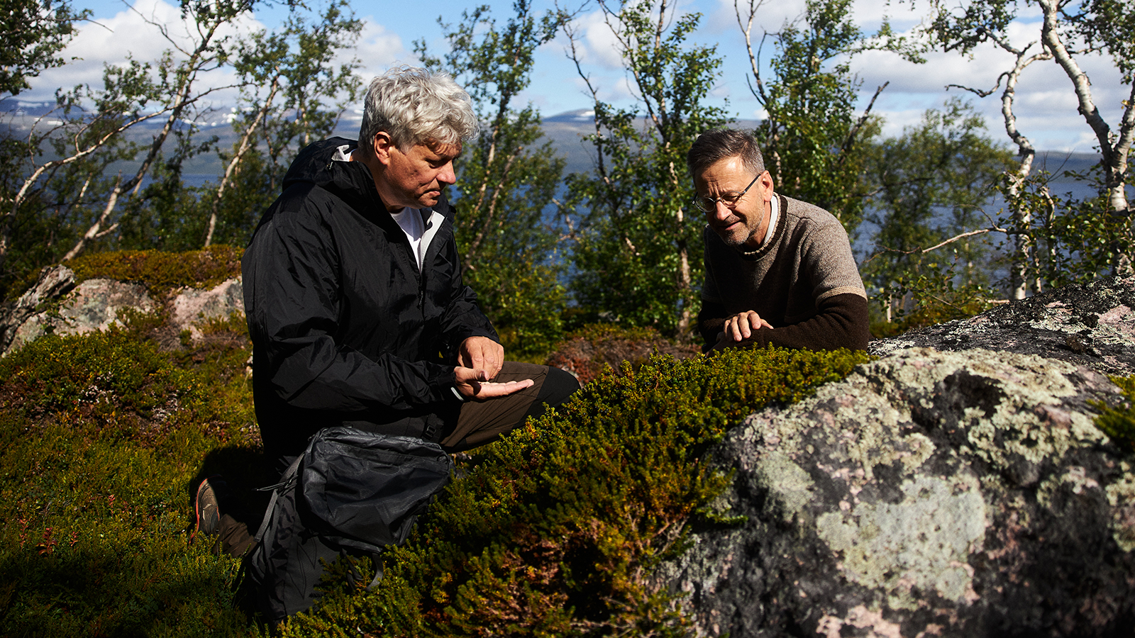 Mission & Purpose 12 Two men closely inspecting plants on a cliff.