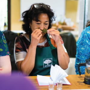 Herbal Schools 36 Woman smelling herbs at a herbal school event, engaging with plants and learning about their uses.